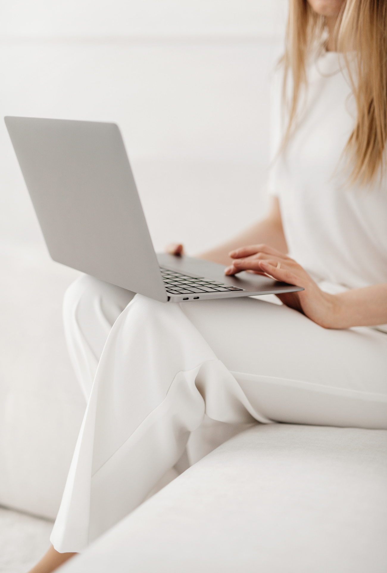 woman seated on sofa on laptop Woman seated on couch using laptop